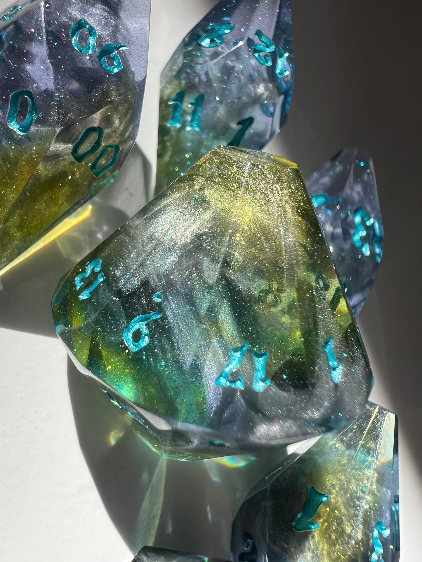 Oversized resin dice with coffin-shaped faces. The dice feature a blue, purple and gold gradient with silver wisps inside.