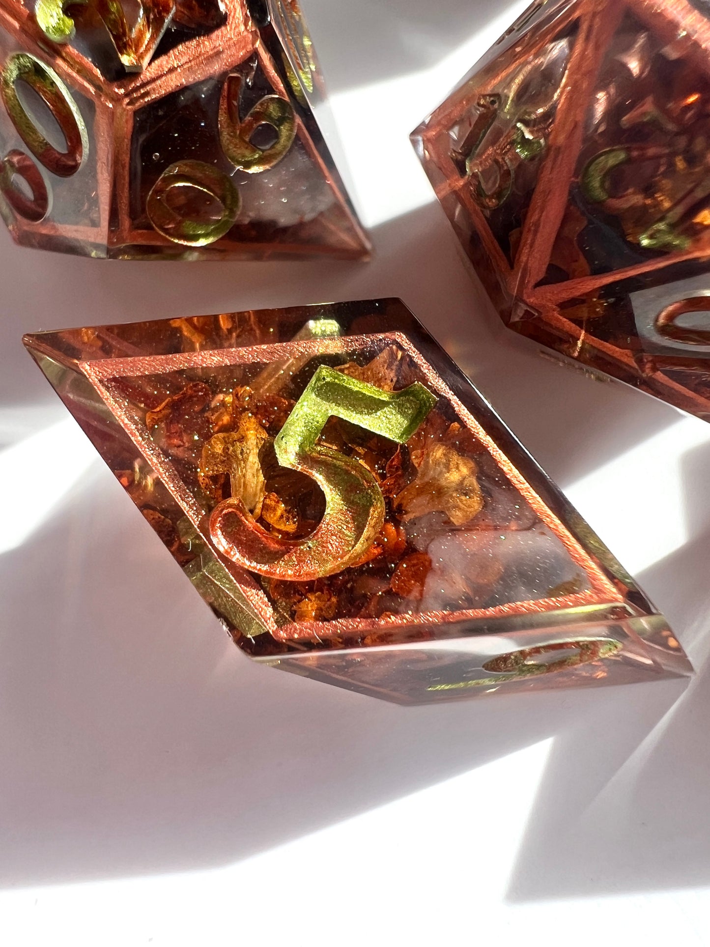 This 7-piece resin dice set includes tiny dried leaves, hand-painted copper borders and gold-to-green gradient numbers.