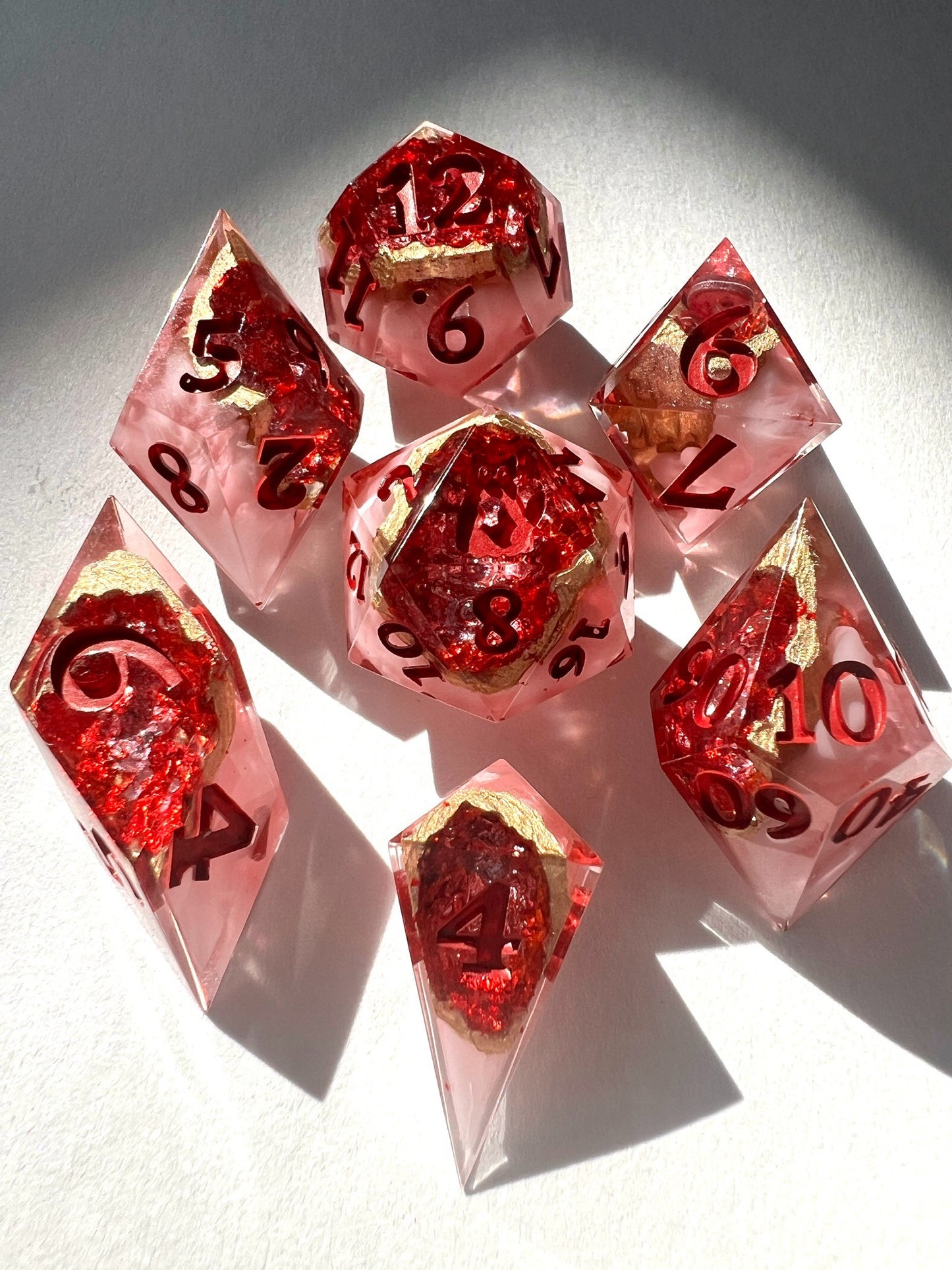 7-piece resin dice set made to look like geodes containing red crystals.