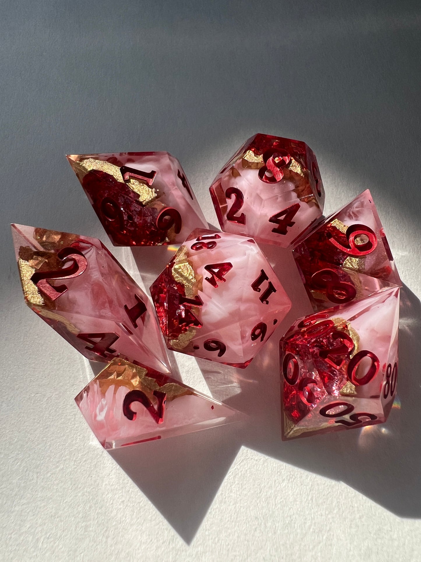 7-piece resin dice set made to look like geodes containing red crystals.