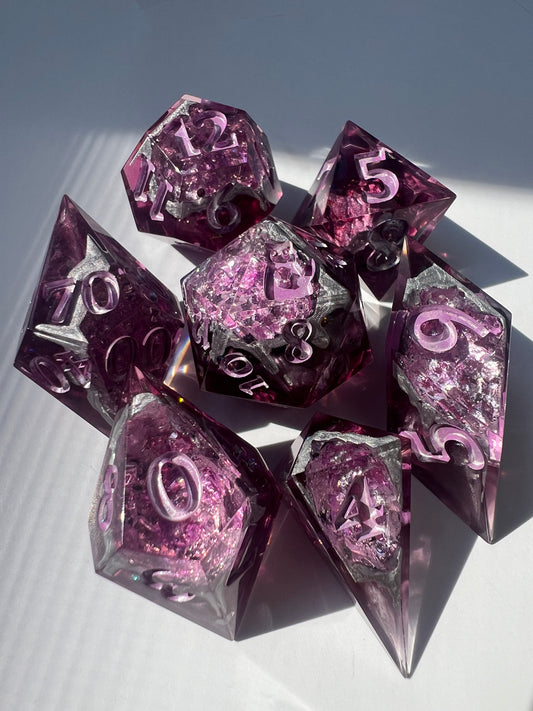 7-piece geode-style dice set containing different shades of pink, silver and purple foil to mimic crystals.