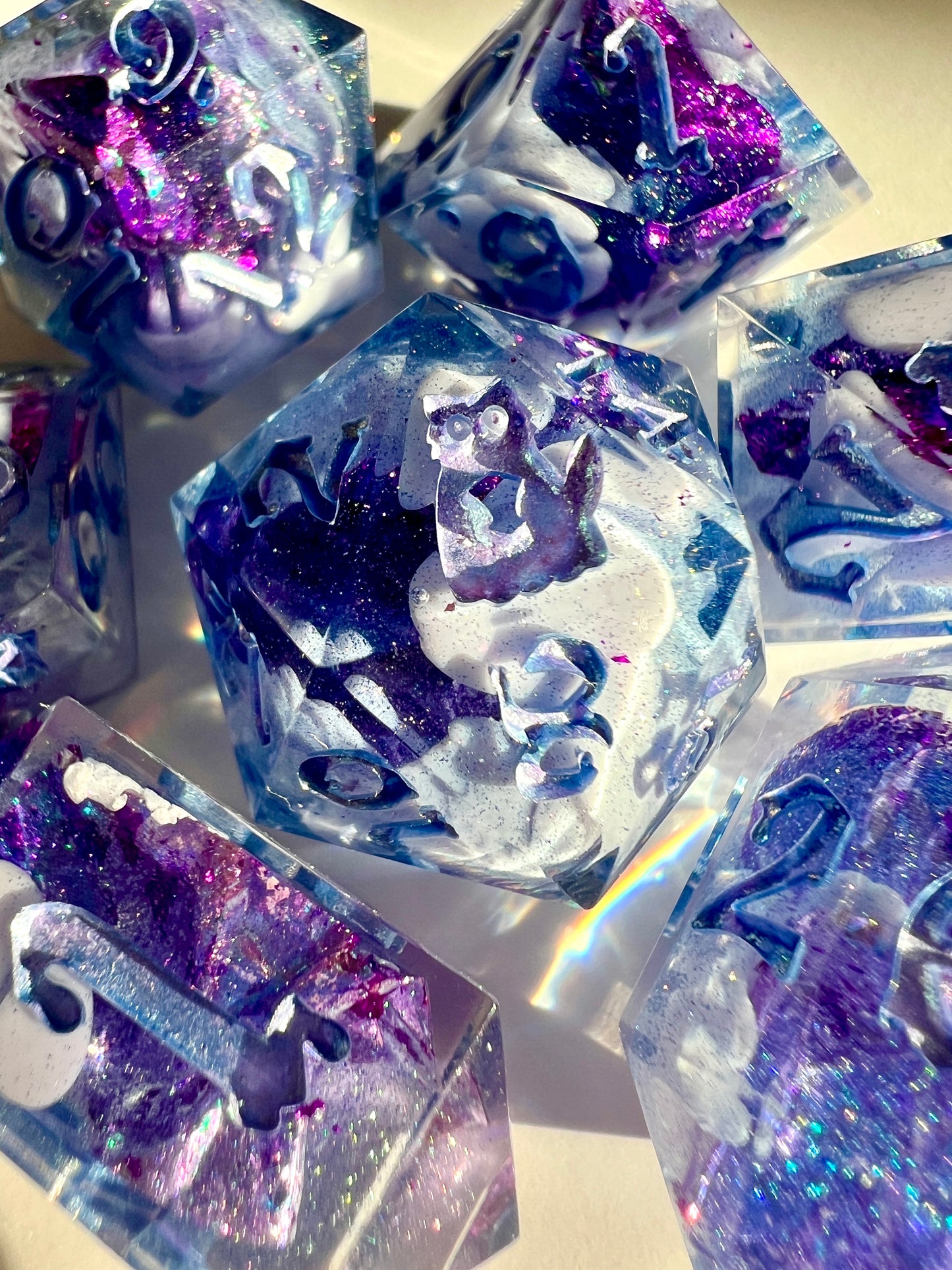 Polyhedral resin dice set with lavender bloops, purple foil and shimmery blue numbers.