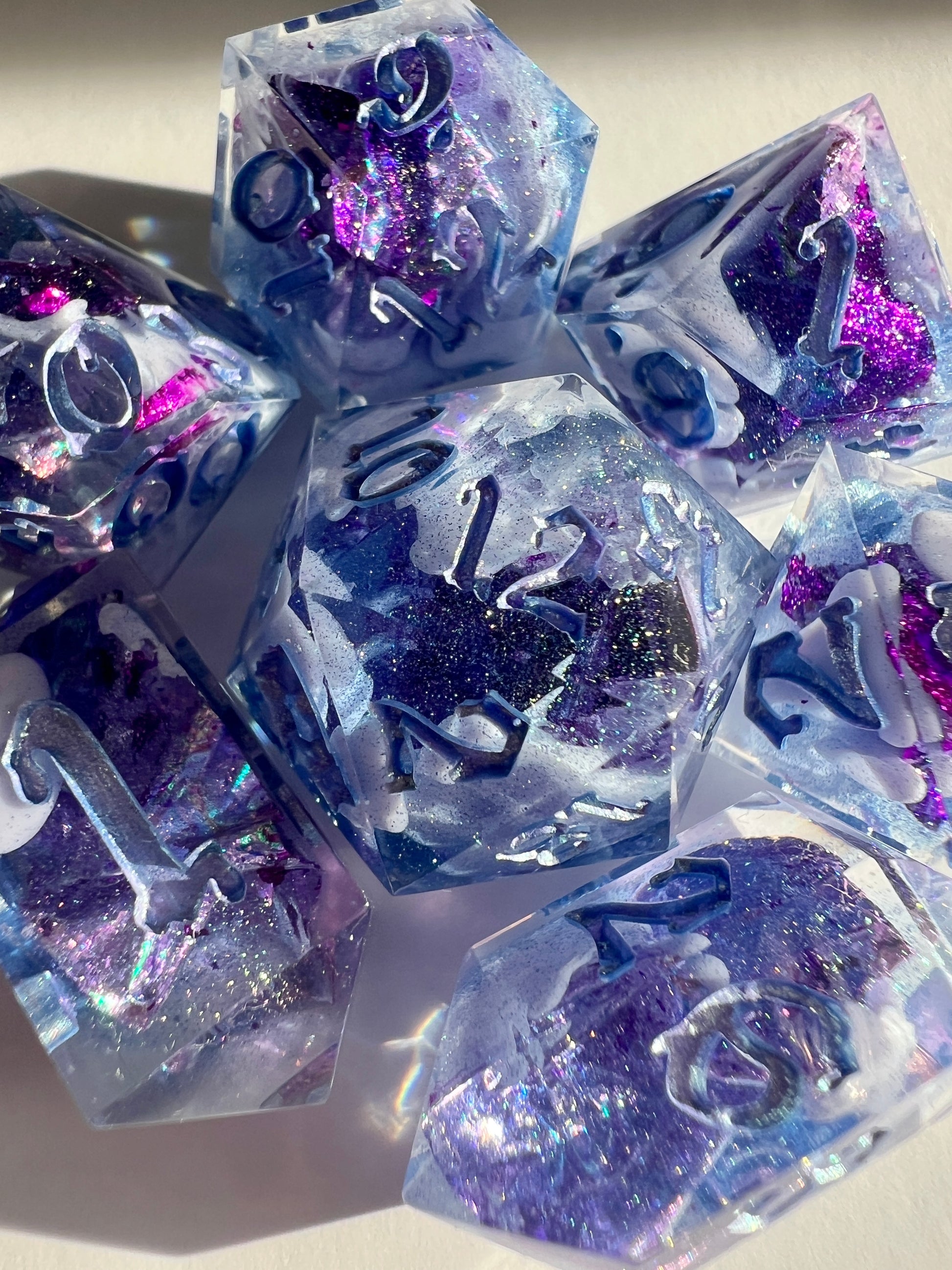 Polyhedral resin dice set with lavender bloops, purple foil and shimmery blue numbers.