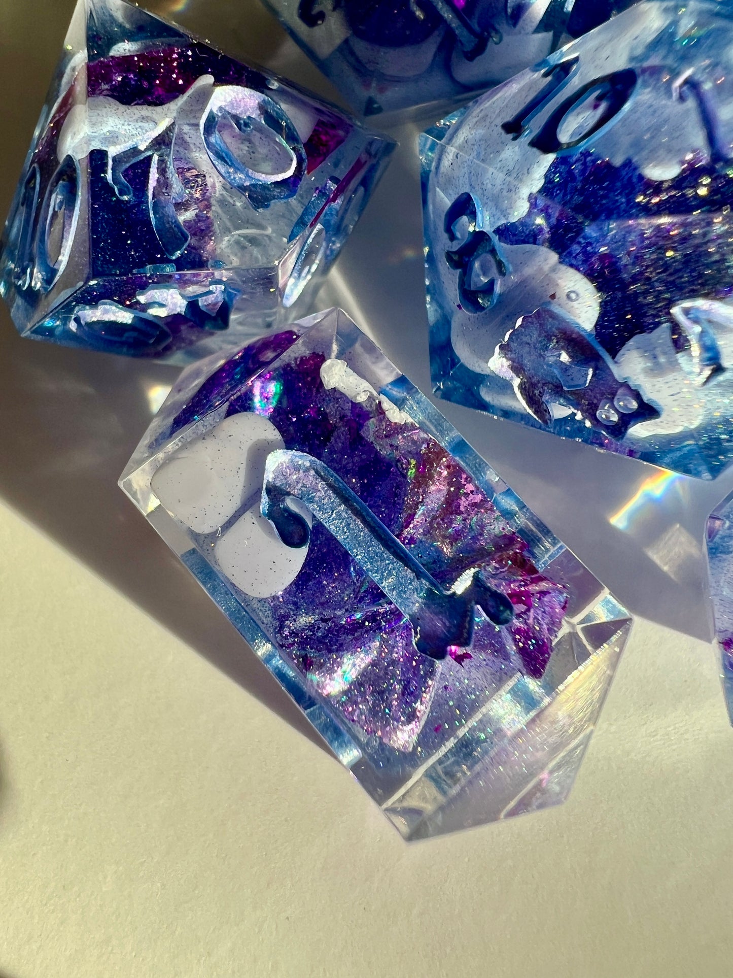 Polyhedral resin dice set with lavender bloops, purple foil and shimmery blue numbers.