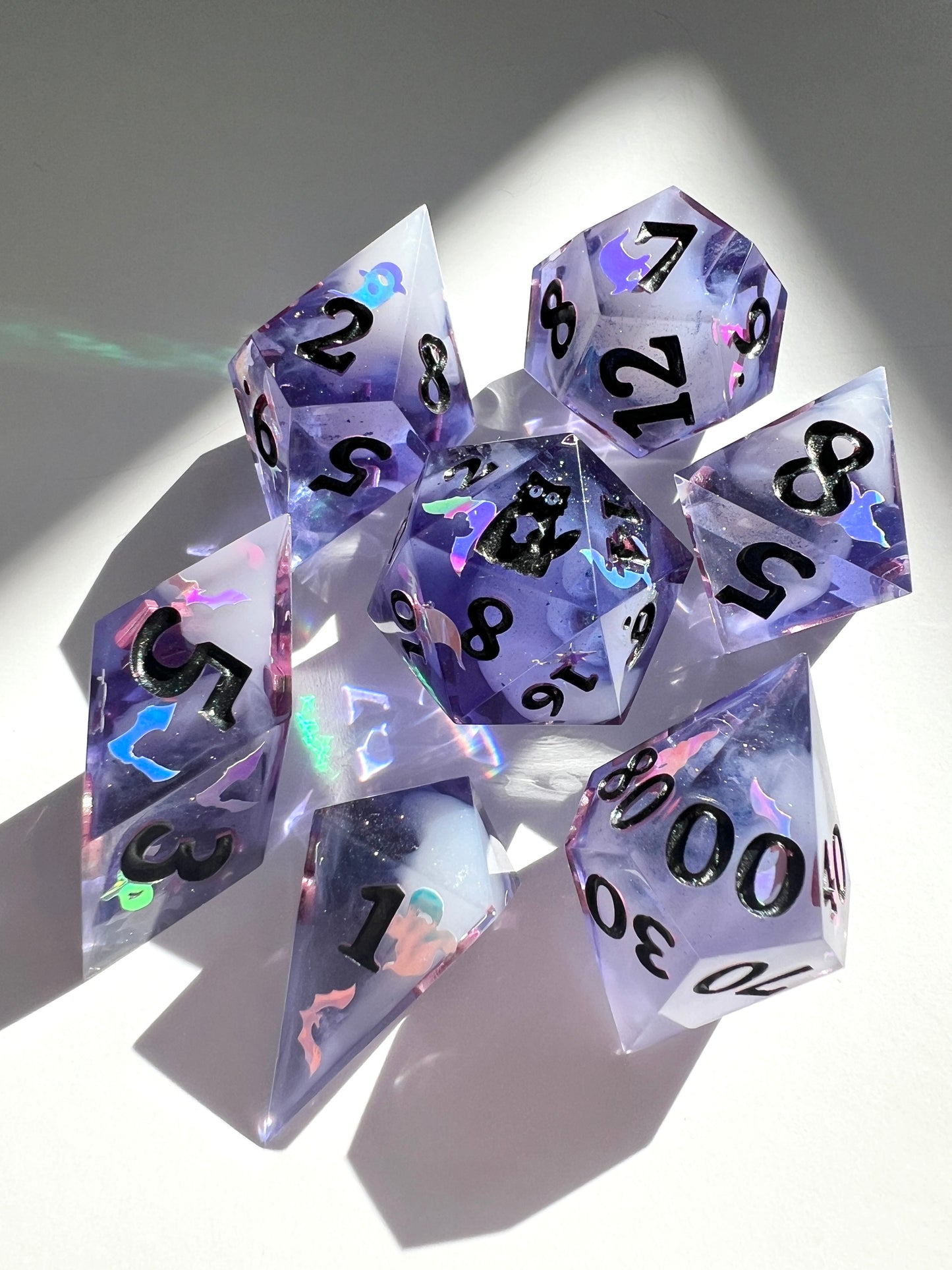 This 7-piece resin set features purple to black gradient dice with cream wisps and holographic bat and ghost decals. 