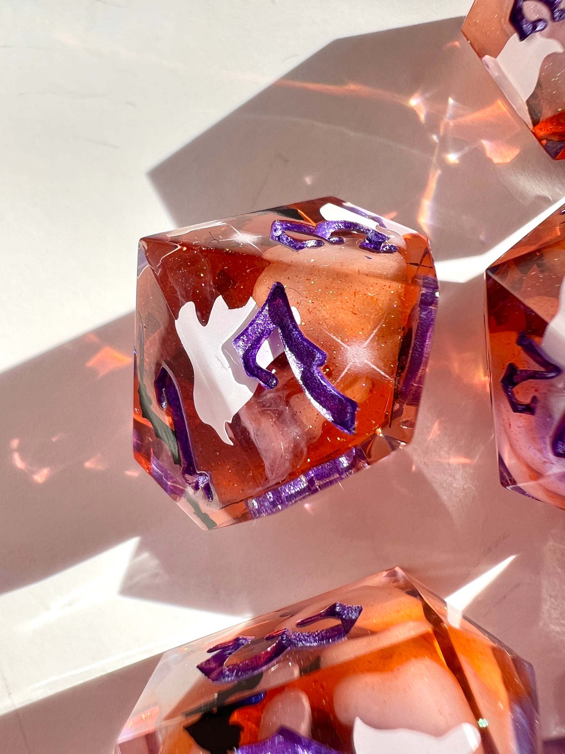 This 8-piece resin dice set features a purple to orange gradient, white wisps, and ghost cat and bat decals. 